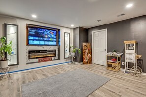 A modern living room with a flat-screen TV, fireplace, and a popcorn cart.