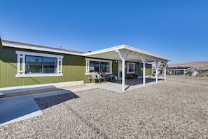A building with a covered patio, a gravel driveway, and a clear blue sky. - 2 Mi to Colorado River! Family Home w/ Fenced Yard (Bullhead City)