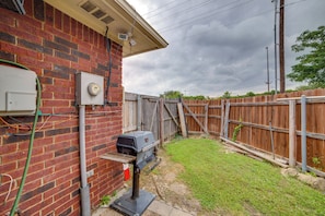 A brick house with a wooden fence, a grill, and electrical boxes.