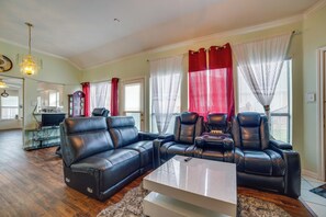 Una sala de estar con un sofá modular, dos sillones reclinables, una mesa de centro y un televisor.
