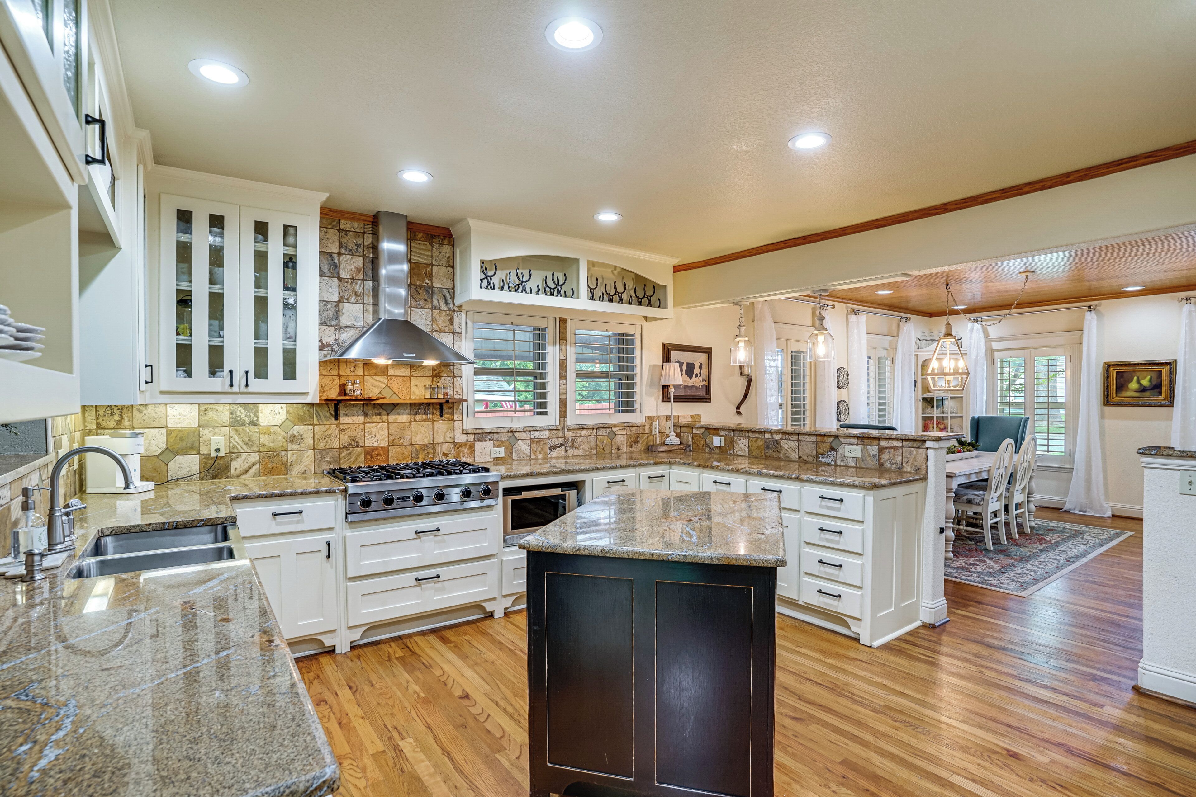 A spacious kitchen with granite countertops, white cabinetry, and a large island.