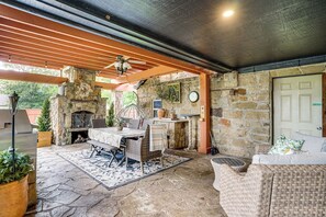An outdoor patio with stone flooring, a stone fireplace, wicker furniture, and a ceiling fan. - Historic Weatherford Estate w/ Backyard Oasis (Weatherford)