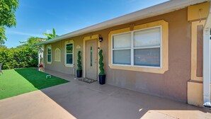 A single-story house with a front porch, a door with a decorative glass panel, a window with blinds, and a small lawn area. - Golf, Beaches & Sunshine! Pet-friendly Naples Home (Naples)
