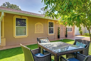 A yellow building with a patio area featuring wicker furniture and a glass table. - Golf, Beaches & Sunshine! Pet-friendly Naples Home (Naples)