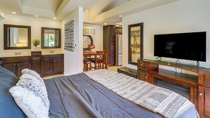 Un dormitorio moderno con una cama grande, televisión y comedor.