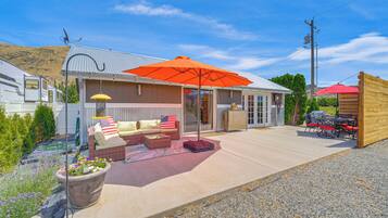 A covered patio area with outdoor furniture, a large umbrella, and a potted plant.