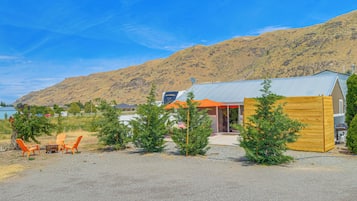 A building with a metal roof, a wooden deck, and a gravel driveway.