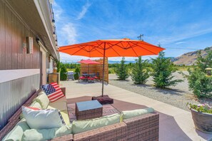 An outdoor patio with wicker furniture, a red umbrella, and a barbecue grill. - Walk to River + Bike Trail! East Wenatchee Escape (East Wenatchee)