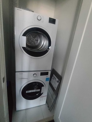 A compact, two-door washer and dryer unit in a narrow hallway.