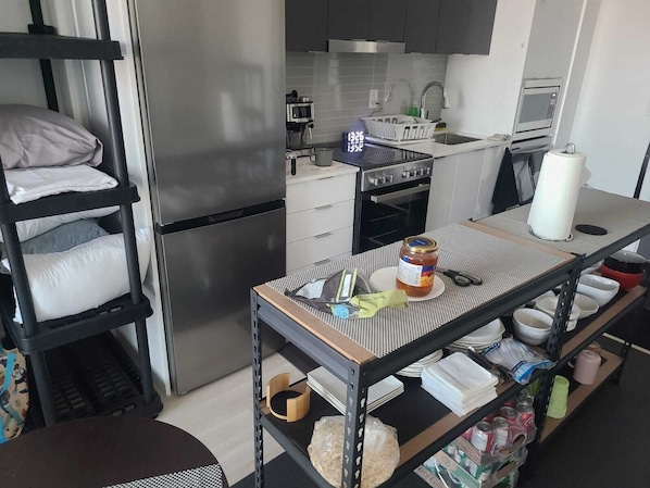A compact kitchen with a refrigerator, stove, microwave, and sink.