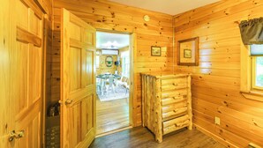 A wooden interior with a door leading to a dining area, a small table, and a bench.