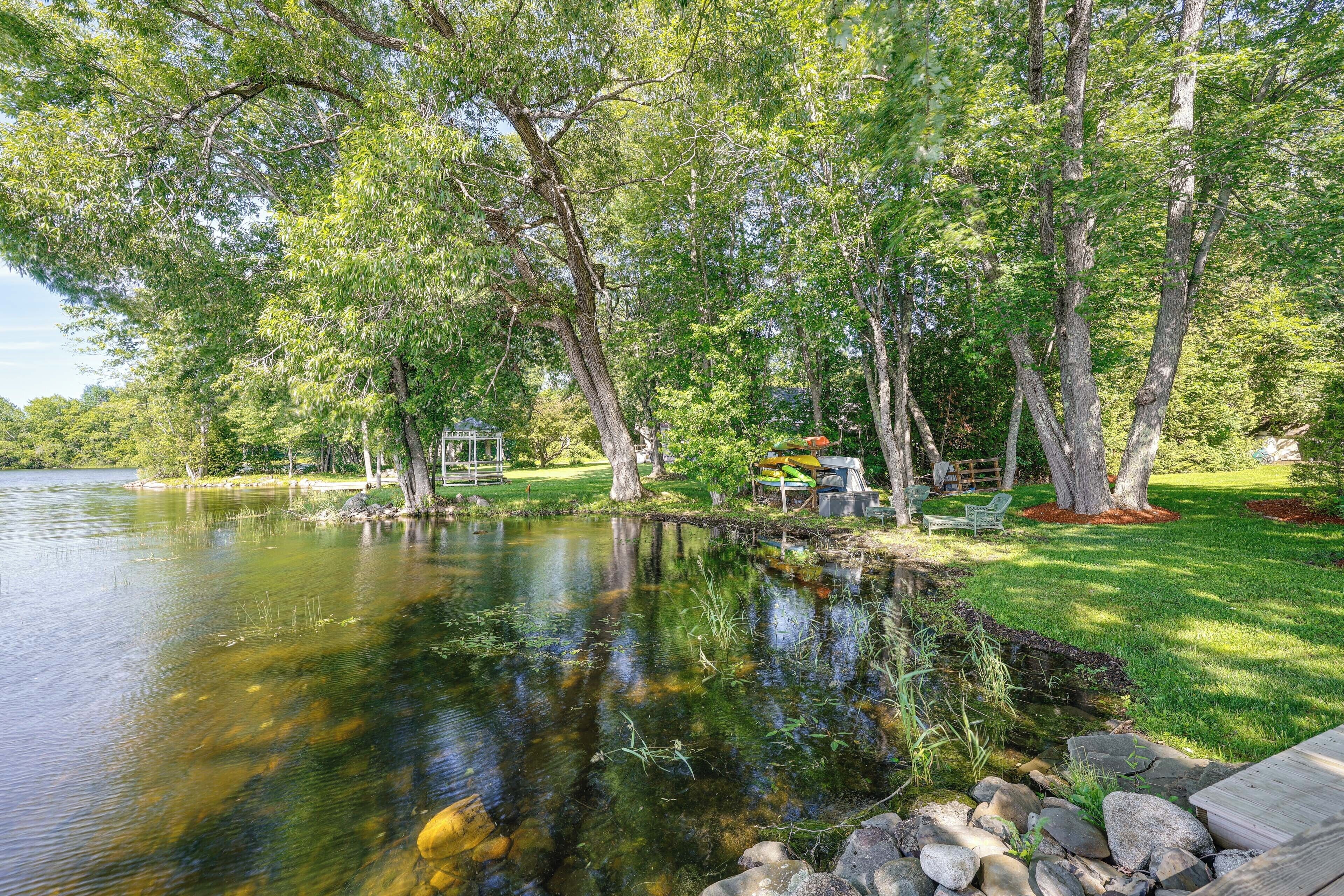 A serene lakeside setting with a wooden deck, a small pond, and lush greenery.