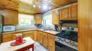 A kitchen with wooden cabinets, a stove, a microwave, and a sink.