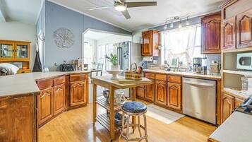 A kitchen with wooden cabinets, a stainless steel refrigerator, a dishwasher, and a ceiling fan.
