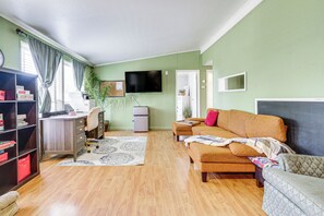 Ein Wohnzimmer mit einer Couch, einem Couchtisch, einem Fernseher, einem Bücherregal und einer Pflanze.