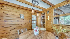 A wooden interior with a round dining table, chairs, hanging light fixtures, and a window with a view. - On-site Fishing! Riverfront Gem w/ Patios in Drake (Drake)