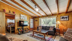 A cozy living room with a sofa, coffee table, and a television. - On-site Fishing! Riverfront Gem w/ Patios in Drake (Drake)