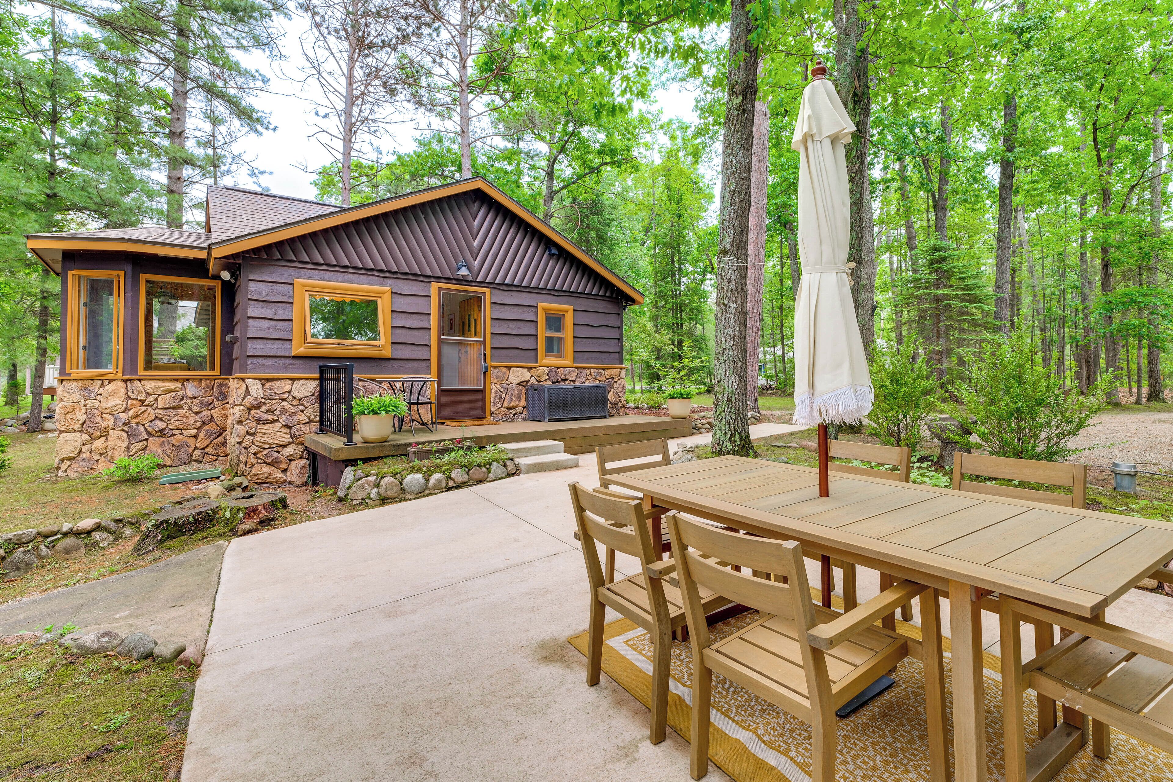 A cabin with a stone foundation, wooden exterior, and a patio with a table and chairs.