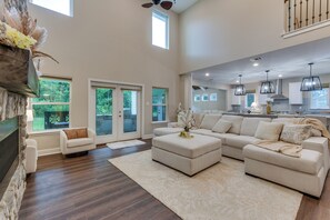 A spacious living room with a sectional sofa, a fireplace, and a view of the kitchen. - On Several Acres! Luxury Home in Prairieville (Prairieville)