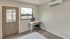 Una habitación con escritorio, silla y aire acondicionado.
