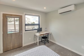 Una habitación con escritorio, silla y aire acondicionado.