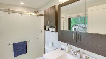 A bathroom with a large mirror, white sink, and dark cabinets.