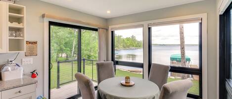 A dining area with a table and chairs, a view of a lake, and a balcony with a railing.