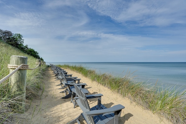 A sandy beach with rows of wooden chairs and a wooden fence. - South Haven Family Lake Getaway 4 Mi to Downtown (South Haven)