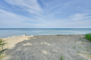 Ein sandiger Strand mit blauem Himmel und ruhiger See.