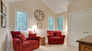 A room with two red sofas, a wooden nightstand, a wall clock, and a white door. - South Haven Family Lake Getaway 4 Mi to Downtown (South Haven)