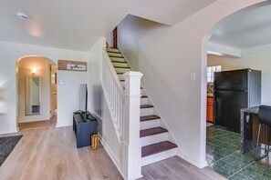 Eine Treppe führt zu einer zweiten Etage, ein Küchenbereich mit Kühlschrank und ein Schild an der Wand mit der Aufschrift 'gather'.