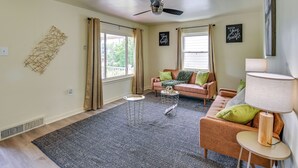 Un salon avec un ventilateur de plafond, un canapé, une table basse et une lampe.