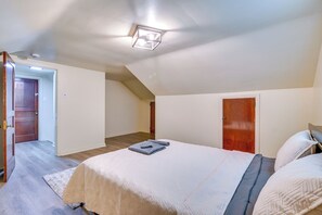 A bedroom with a bed, a door, and a ceiling light fixture.