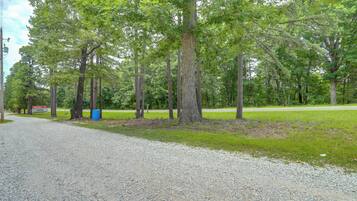 A gravel path leading through a wooded area with trees and a sign in the distance.