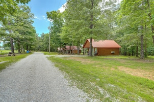 A gravel path leading to a cabin with a red roof, surrounded by trees.