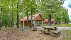 A cabin with a picnic table and a fire pit in a wooded area. - Near Trails! Ozark Mtn Hideaway w/ Fire Pit, Grill (Fifty-Six)