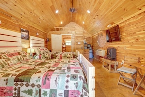 A wooden cabin interior with a large bed, a television, and a small kitchenette. - Adventure Awaits! Fifty-six Cabin Near Caverns (Fifty-Six)