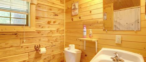 A wooden cabin bathroom with a toilet, sink, and mirror.