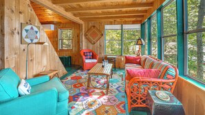 A cozy room with a wooden ceiling, a colorful patterned rug, a sofa, a chair, and a table. - Waterfront Sand Pond Cabin w/ Views & Fire Pit (Litchfield)