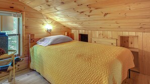 A wooden cabin bedroom with a bed, a window, and a wall-mounted light. - Waterfront Sand Pond Cabin w/ Views & Fire Pit (Litchfield)