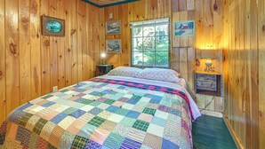A wooden-paneled room with a bed, a window, and a wall-mounted lamp. - Waterfront Sand Pond Cabin w/ Views & Fire Pit (Litchfield)