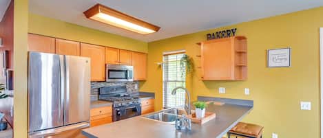 Una cocina con una isla central, armarios de madera, electrodomésticos de acero inoxidable y un letrero que dice 'BAKERY'.