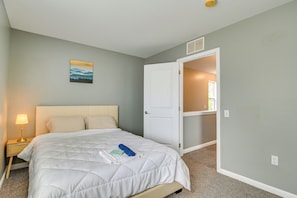 A bedroom with a bed, a nightstand, a lamp, a painting, and an open closet door.