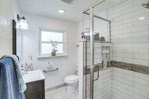 A bathroom with a white sink, toilet, and glass shower enclosure.