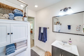 A bathroom with a white vanity, a mirror, a sink, and towels.