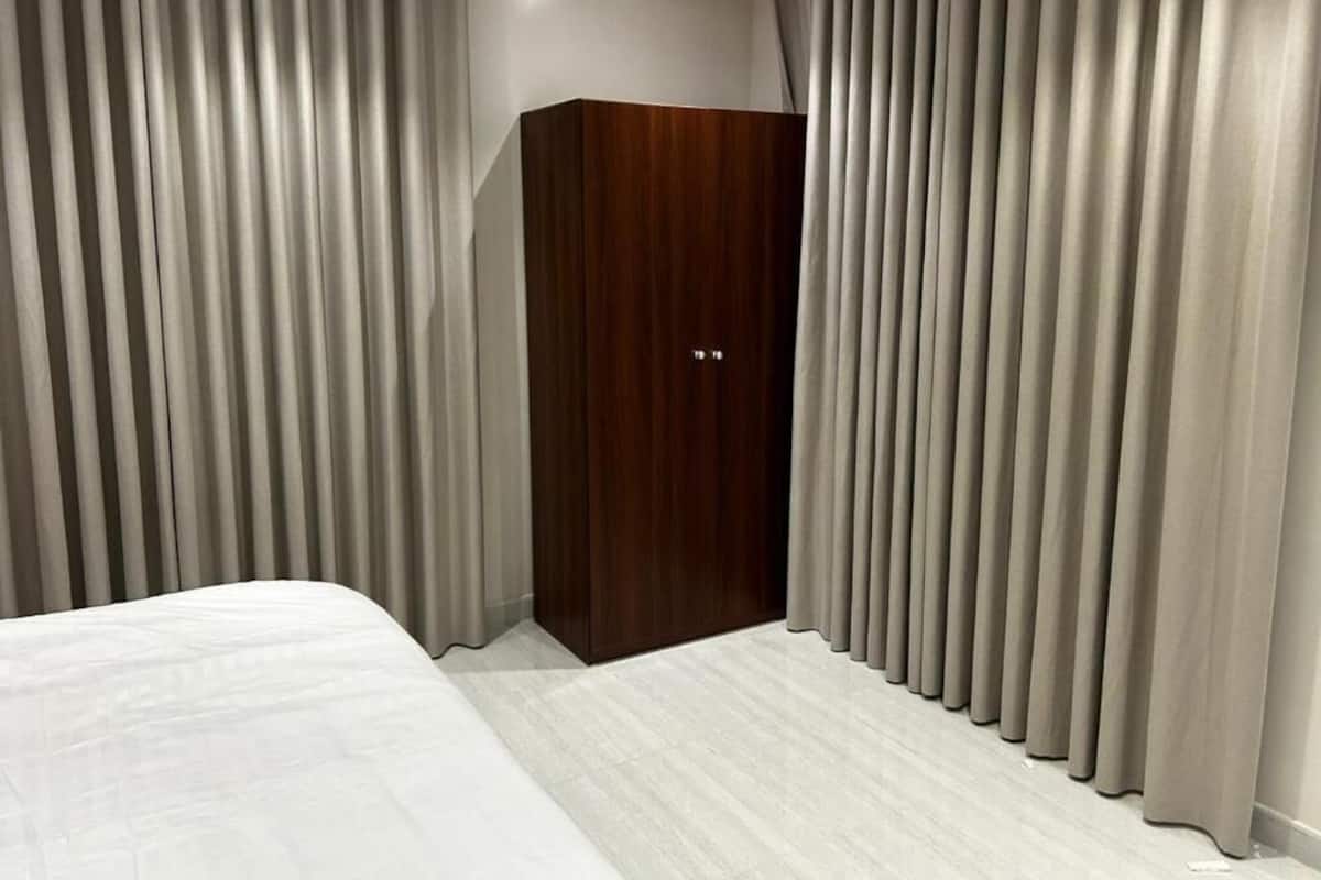 Un dormitorio con cama, armario de madera y cortinas.