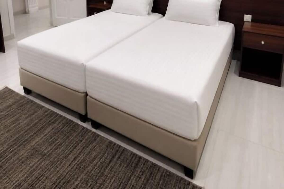 Una cama doble con cabecera de madera, una mesita de noche y suelo alfombrado.