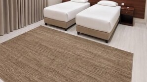 A modern hotel room with two beds, a wooden headboard, a large rug, and an air conditioning unit. - OrbitNet - Anwarat (madina)
