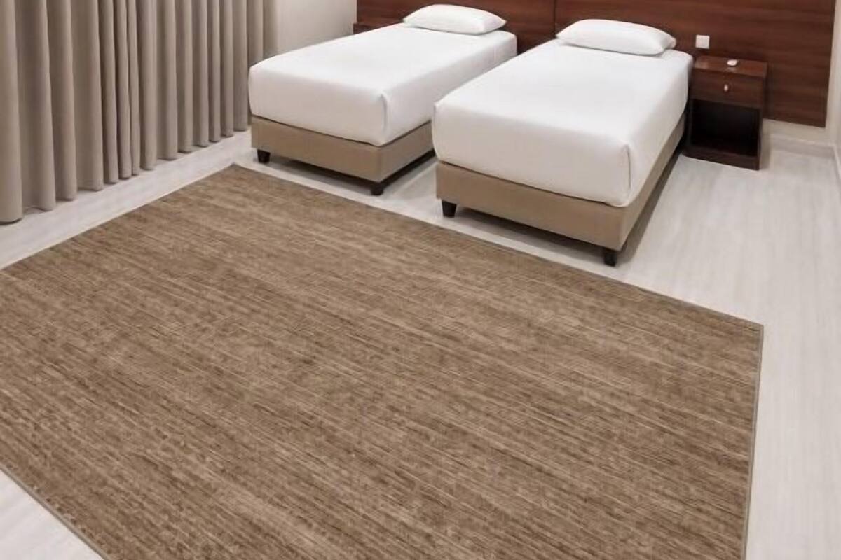 Una habitación de hotel moderna con dos camas, un cabecero de madera, una alfombra grande y un equipo de aire acondicionado.