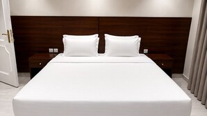 Una cama grande con cabecera de madera, dos mesitas de noche y una puerta.